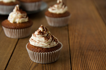 Chocolate cupcakes with whipped cream on rustic wooden table. Homemade dessert. Copy space.