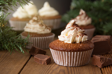 Chocolate cupcakes with whipped cream on rustic wooden table. Homemade dessert.