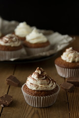 Chocolate cupcakes with whipped cream on rustic wooden table. Homemade dessert.