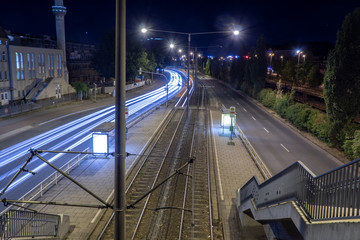 Night scene of a deserted tram station with light trails of an incoming tramcar