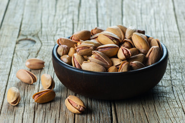 Pistachio in nutshell in wooden bowl on wooden backdrop, composition of pistachios great for healthy and dietary nutrition. Concept of nuts
