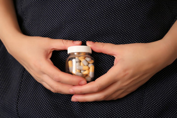 Pills in female hands close-up, woman holding bottle with capsules. Concept of drugs, medication for stomach, vitamins for pregnant women
