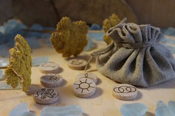 Wooden handmade witch runes with a linen pouch, blue cristals and yellow flowers in a rustic style