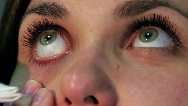 Facial Treatment on a woman's eye area as her lids and under-eye area are being massaged by the fingers of a beauty, woman removing eye make up from her eyes, eyelid massage, hygiene of eyes