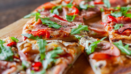 slices Pizza with Mozzarella cheese, mushrooms, ham, tomato sauce, salami, pepper, Spices and Fresh arugula. Italian pizza on wooden table background