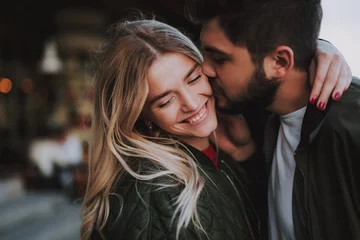 Tuinposter Beautiful young couple expressing their feelings on the street © Yakobchuk Olena