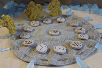 Wooden handmade witch runes with a linen pouch, blue cristals and yellow flowers in a rustic style