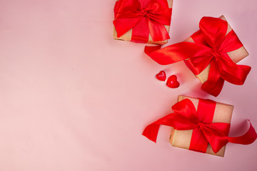 Gift box with red bow ribbon and paper heart on wooden table for Valentines day.