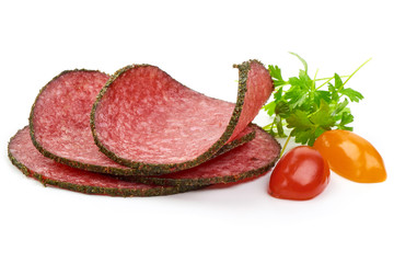 Sliced Milano Salami with parsley and tomatoes, isolated on a white background. Close-up