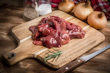 Selbstklebende Fototapeten Raw chicken liver on cutting board. © Arkadiusz Fajer