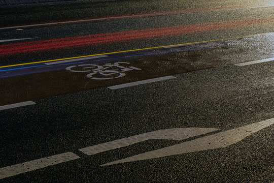 Fahrradsymbol mit Radweg und Abbiegepfeil auf der nassen Stra&szlig;e in Paderborn bei Nacht