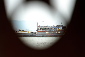 Looking through a window up close blurring the window and focusing on the distant old wooden ship