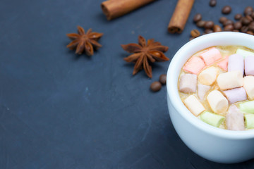 coffee drink with marshmallows and spices. on a dark background. view from above. copy space. morning refreshing drink.