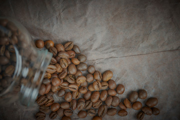 roasted coffee beans poured from a glass jar. angular placement of the coffee object. on dark...