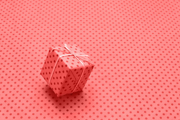 Living Coral color of the Year 2019, Gift box in motion on wrapping paper with polka dots....