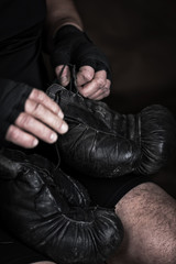 athlete puts on black leather boxing gloves