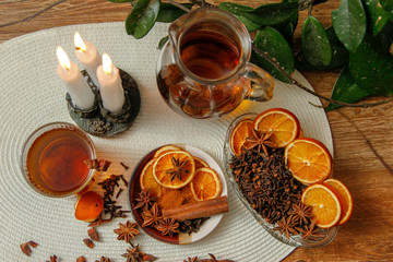 Beautiful composition with anise, cloves, cinnamon stick and powder, tea and dried orange. Wooden table, rustic background and candle light. Close-up.