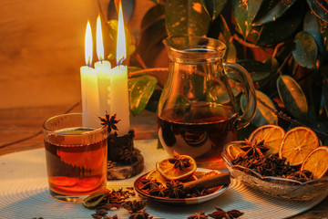 Beautiful composition with anise, cloves, cinnamon stick and powder, tea and dried orange. Wooden table, rustic background and candle light. Close-up.