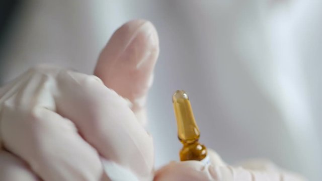 A medic in gloves breaks off the edge of a glass ampoule.