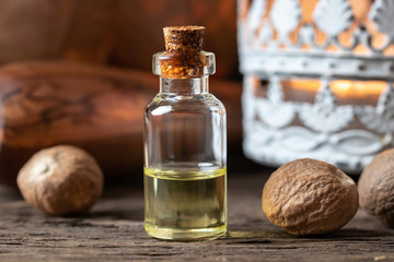 A bottle of nutmeg essential oil with nutmeg - obrazy, fototapety, plakaty