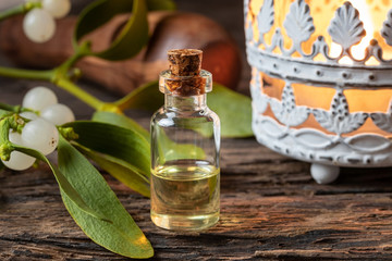 A bottle of essential oil with fresh mistletoe twigs