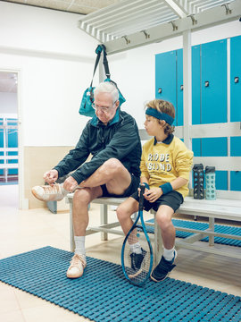 Old man with tennis racket near boy