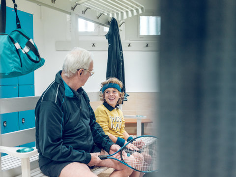 Old man with tennis racket near boy