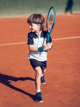 Boy playing tennis on hard court