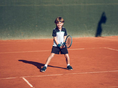 Boy playing tennis on hard court