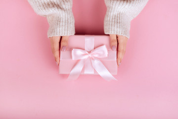 Female hands holding a small gift wrapped with pink ribbon. Selective focus,Selective focus