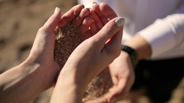 The girl pours sand in man's hands