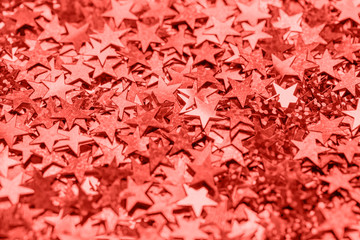 Trendy living coral color of the year 2019 star shaped festive confetti background, close up with copy space