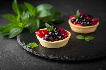 Pastry berry tart. Delicate crispy, crumbly dessert with black and red currants and mint. Assorted Confectionery Range.