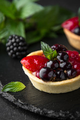 Pastry berry tart. Delicate crispy, crumbly dessert with black and red currants and mint. Assorted Confectionery Range.