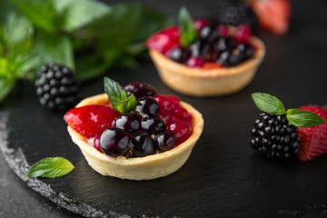 Pastry berry tart. Delicate crispy, crumbly dessert with black and red currants and mint. Assorted Confectionery Range.