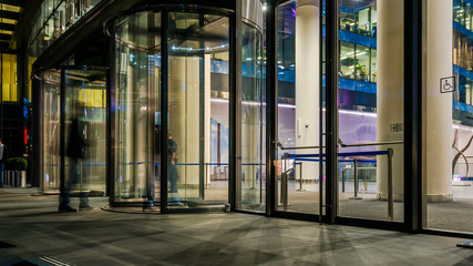  the flow of people passing through the revolving door of the modern office building at the end of...