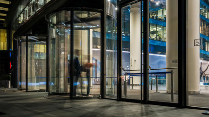  the flow of people passing through the revolving door of the modern office building at the end of...
