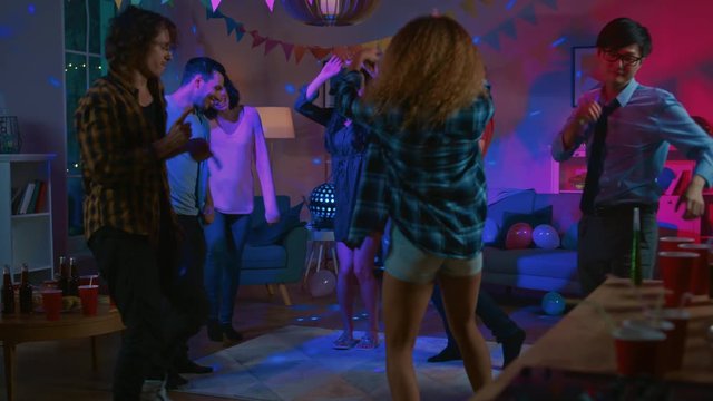 At the College House Party: Diverse Group of Friends Have Fun, Dancing and Socializing. Boys and Girls Dance in the Circle. Disco Neon Strobe Lights Illuminating Room. 