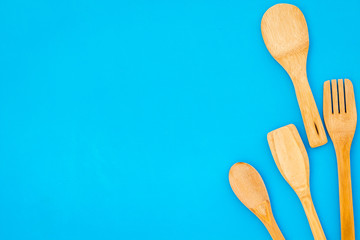 woodenware set with spoon, fork on blue backgtound top view space for text