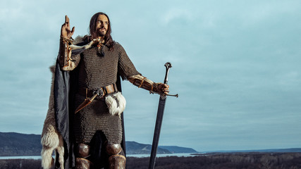 Long haired knight with the two-handed sword. Panorami? view on the background.