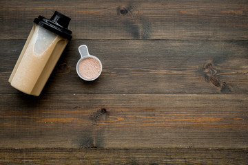 sport nutrition set with protein powder for cocktail and scoop on wooden background top view space for text