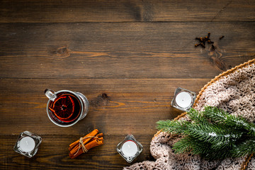 Hot beverage for warm winter evening. Mulled wine near cinnamon, fir branches, wool blanket, candles on dark wooden wooden background top view copy space
