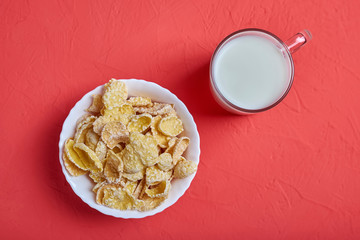 Cup of milk and corn flakes in white bowl