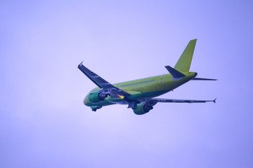 takeoff of a green passenger airplane against a purple sky