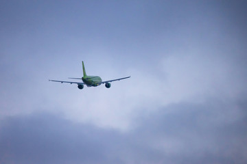 Fototapeta na wymiar back view of a departing passenger airplane against a gloomy cloudy sky
