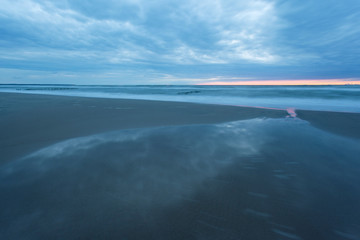 landscape at dusk, sandy beach and a smooth sea surface during the "blue hour" on a long exposure