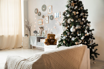 Bright New Year celebration decor. Light room with christmas interior, Xmas Tree decorated with flashing garland and balls