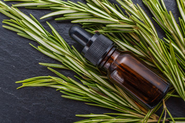 Rosemary essential oil on dark stone background