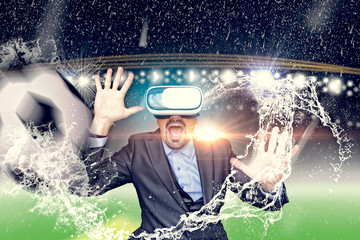 Business man with virtual reality glasses in a stadium with rain and a ball. Mixed Media