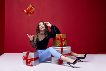 Beautiful young pretty woman with a bright evening make-up of shiny red lipstick on the lips brunette curly hair festive mood winter Christmas New Year St. Valentine's Day and birthday gift surprise.